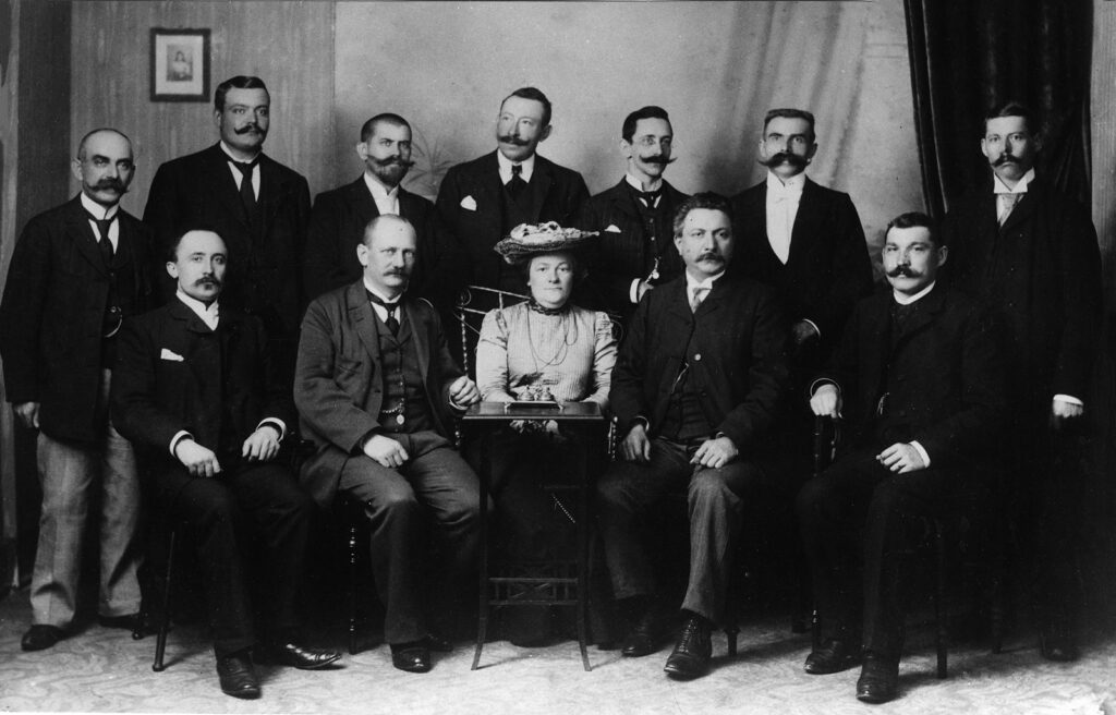 Gruppenbild, 12 Männer, Mitglieder der Reichtagsfraktion - und in deren Mitte sitzt Clara Zetkin
