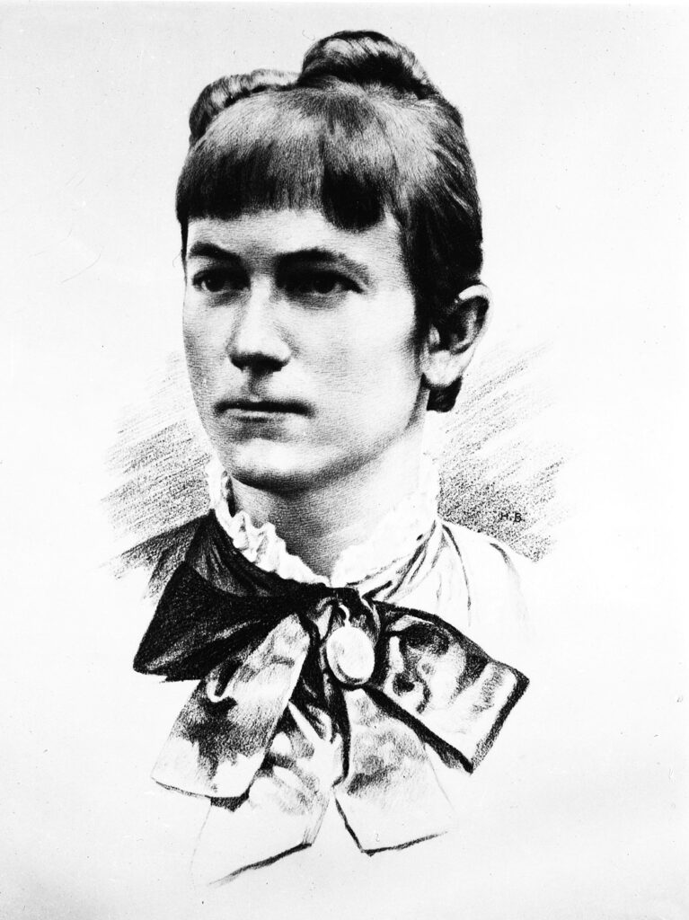 Schwarz-weiss Porträt der jungen Clara Zetkin, hochgesteckte Haare mit Brosche und Schleife um den Hals